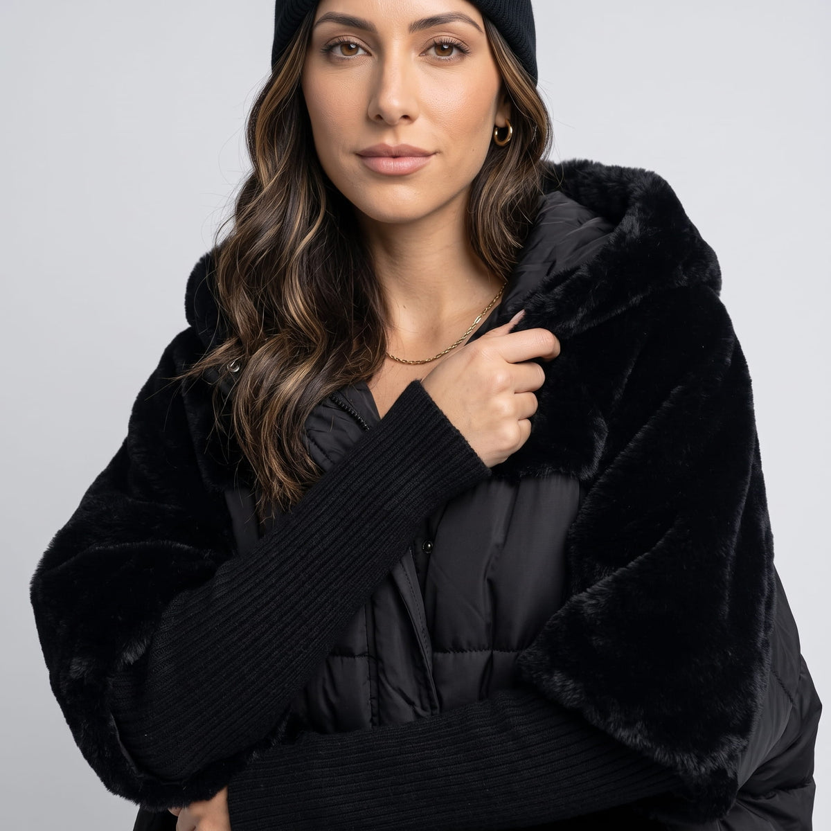 Close-up of black plush sleeve and ribbed knit cuff on a quilted parka