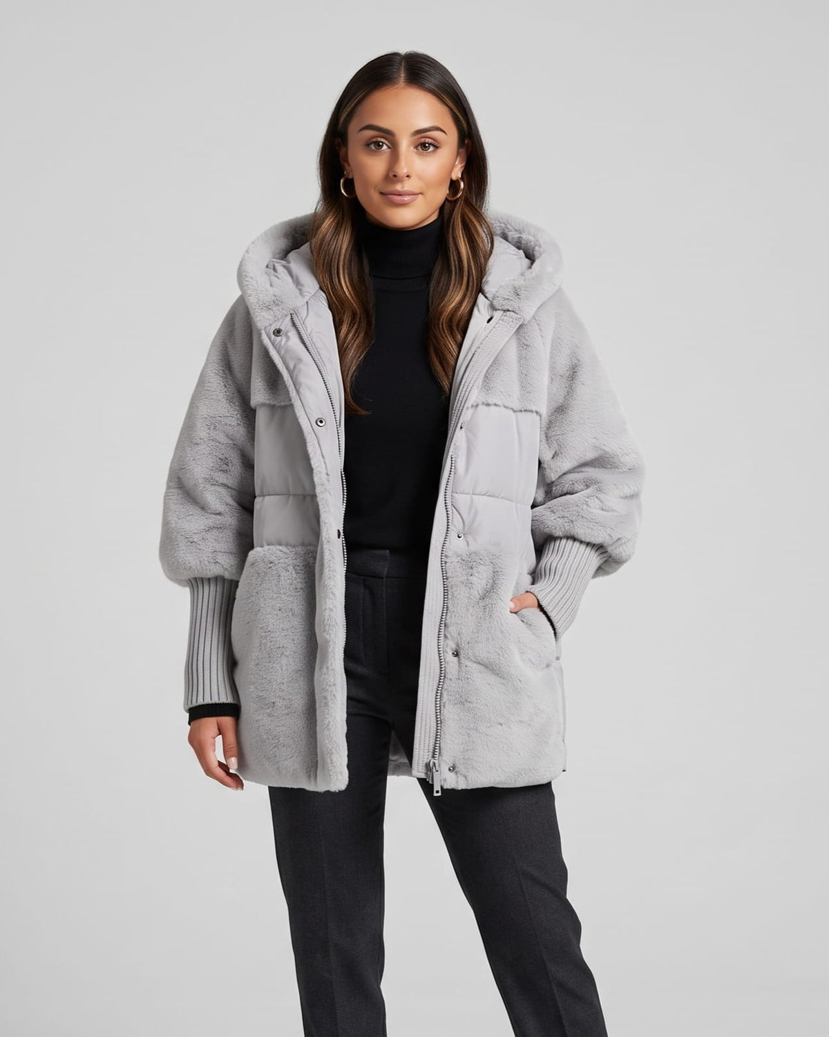 Woman in gray oversized hooded puffer parka with plush panels over dark trousers