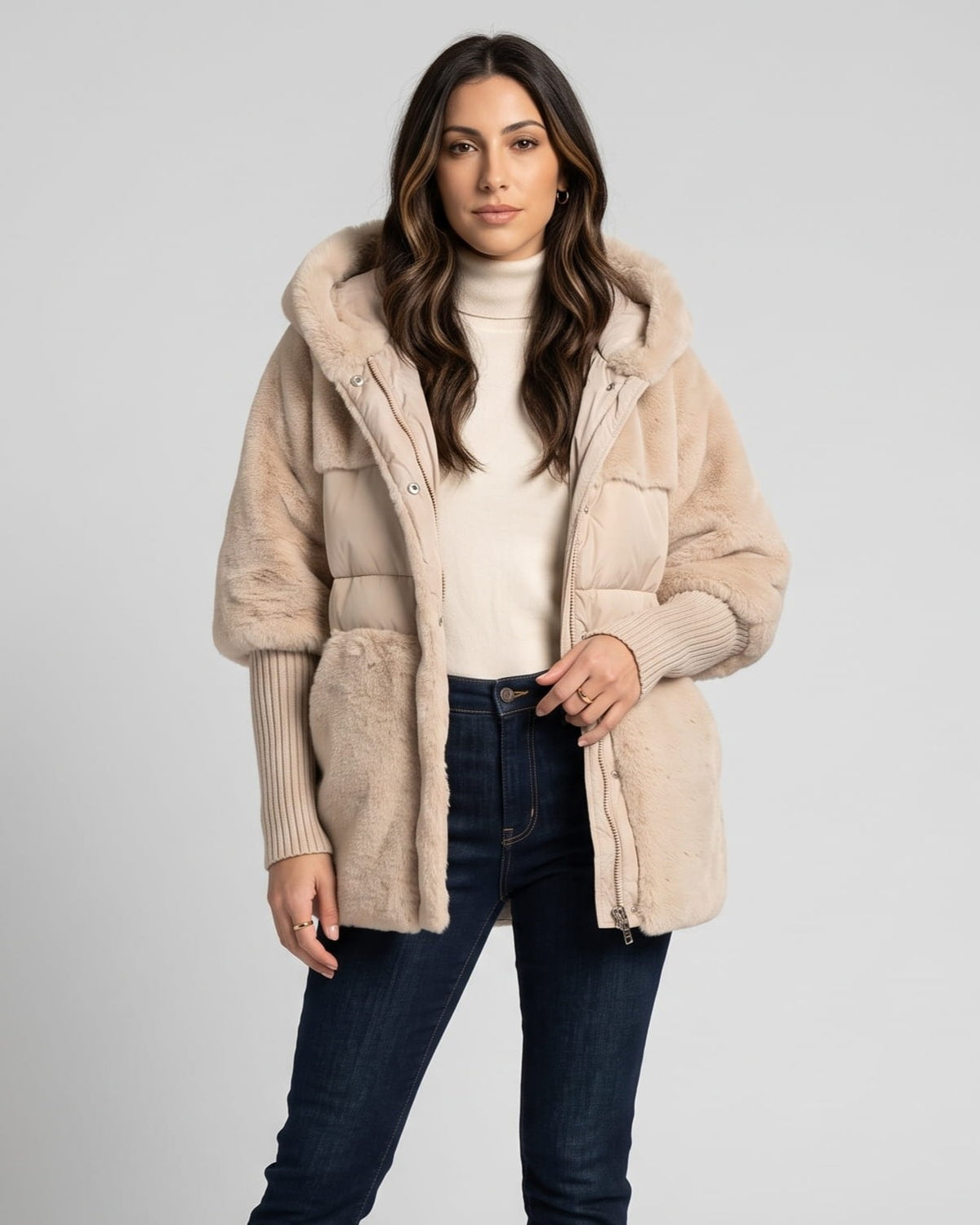 Woman in light beige hooded puffer parka over a cream turtleneck and jeans