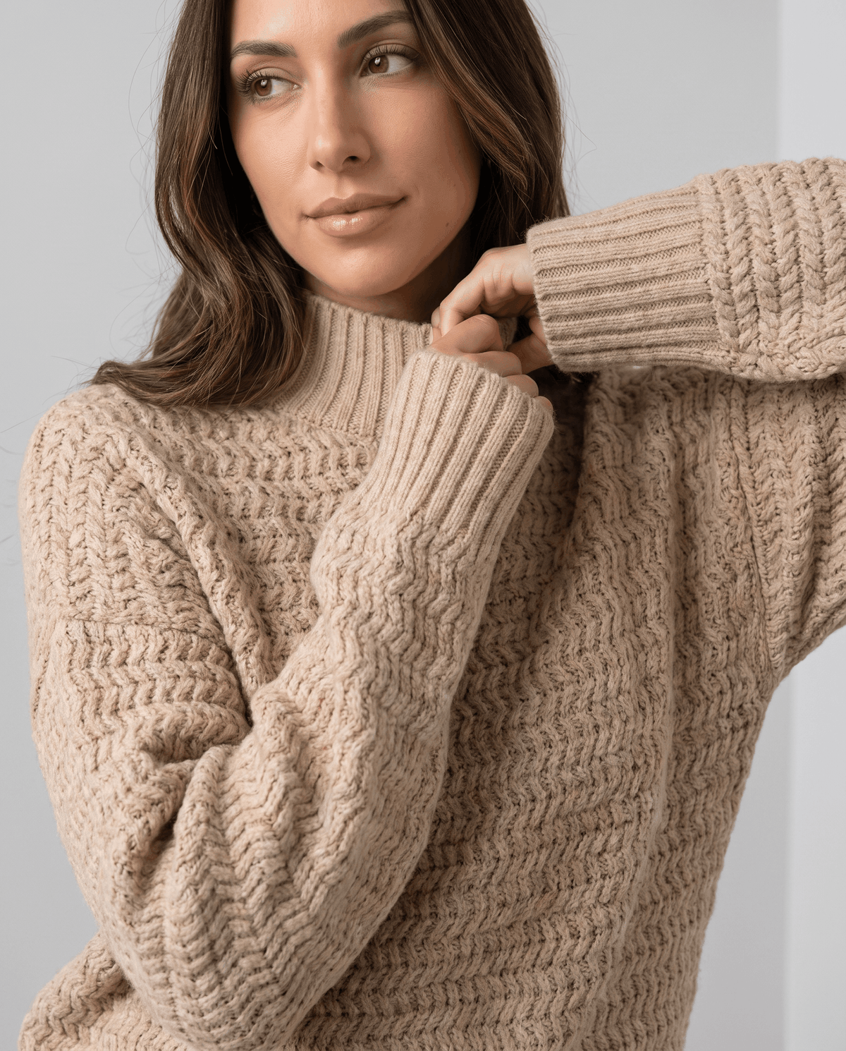 Close-up of model at the ribbed collar of a beige textured knit