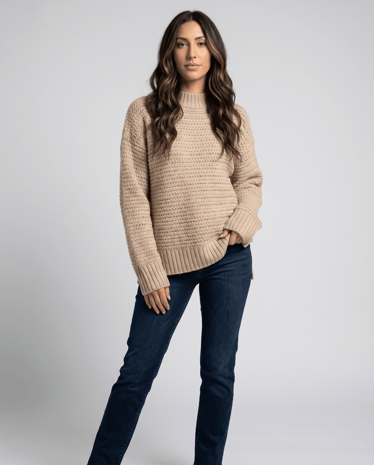 Front view of beige oversized mock neck sweater with dark wash jeans
