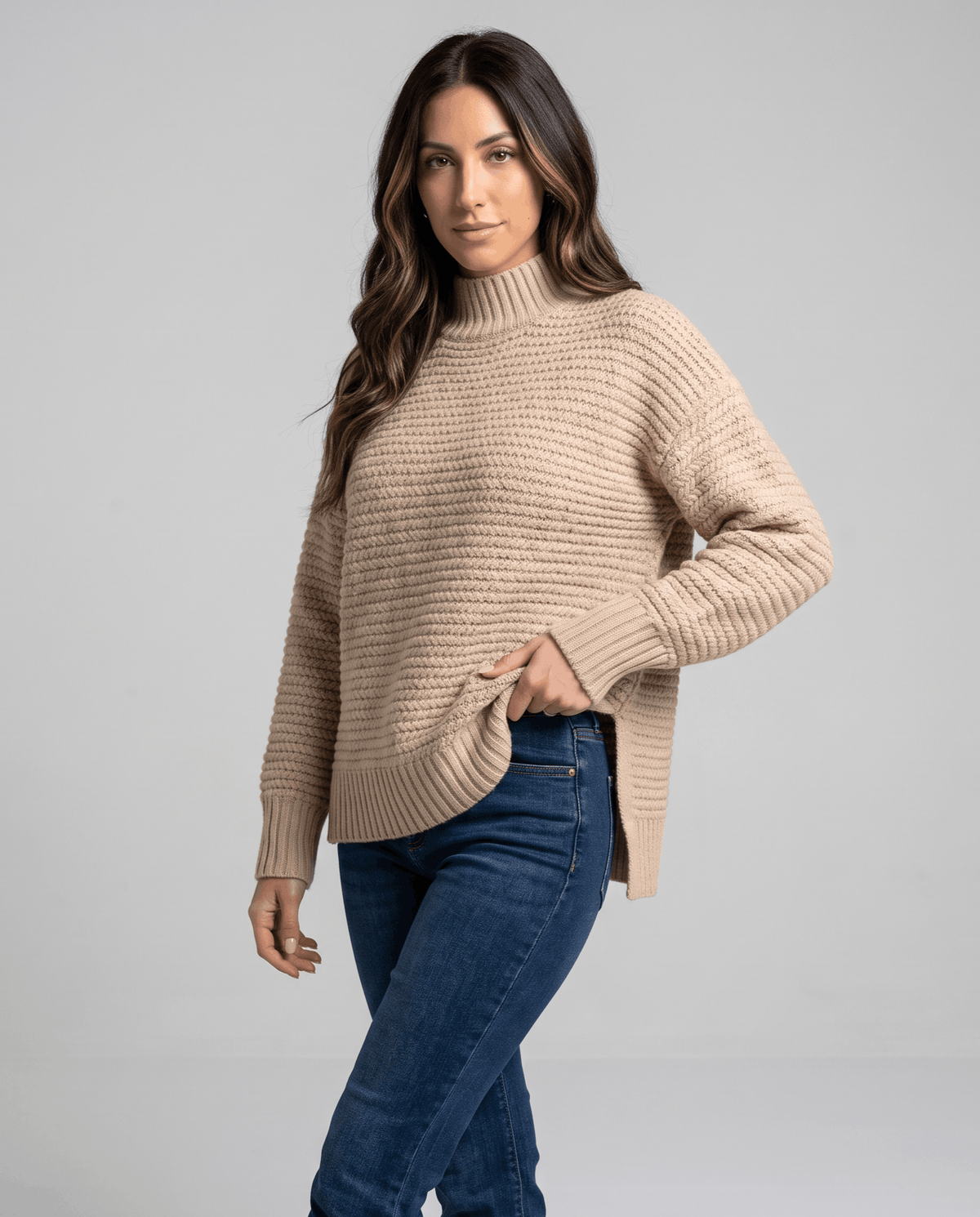 Side view of beige oversized sweater showing side slit with light jeans