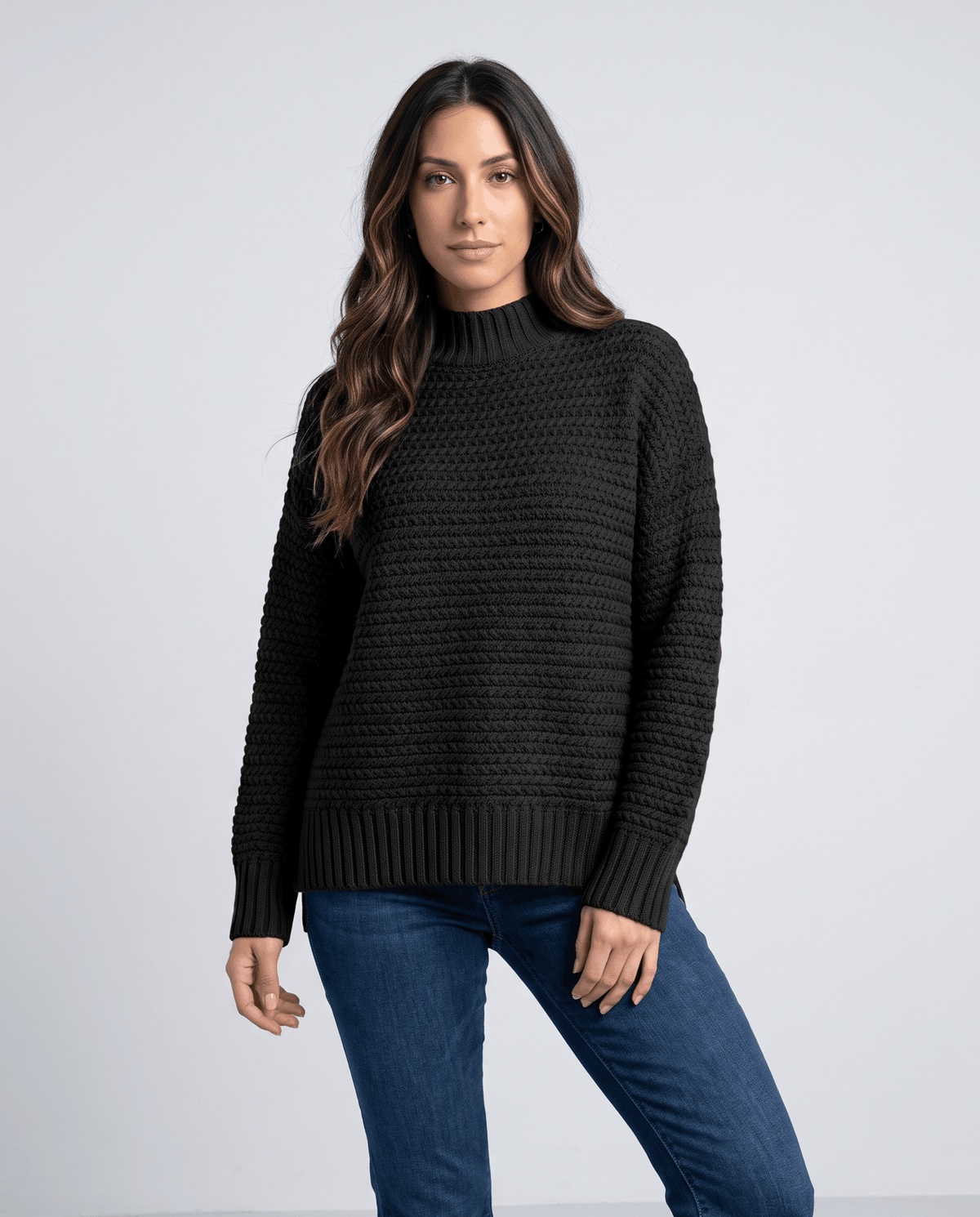 Front view of black oversized mock neck sweater worn with medium wash jeans