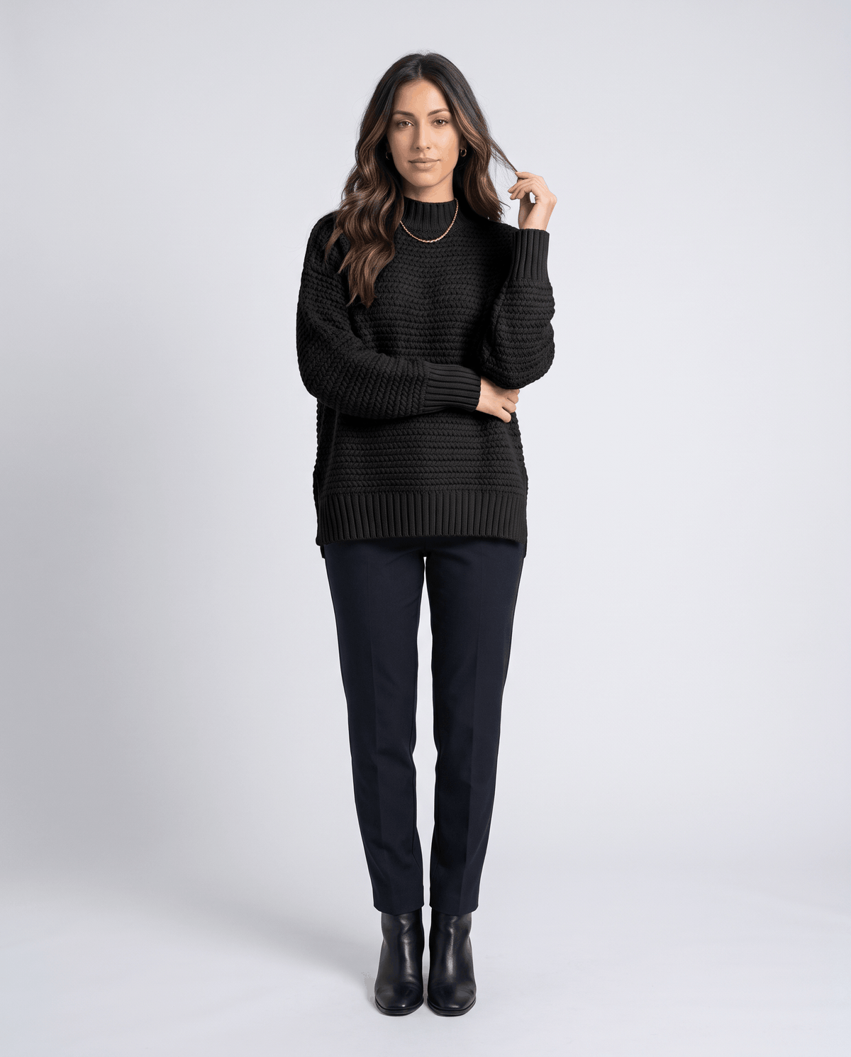 Full-length view of black mock neck sweater with black pants and ankle boots