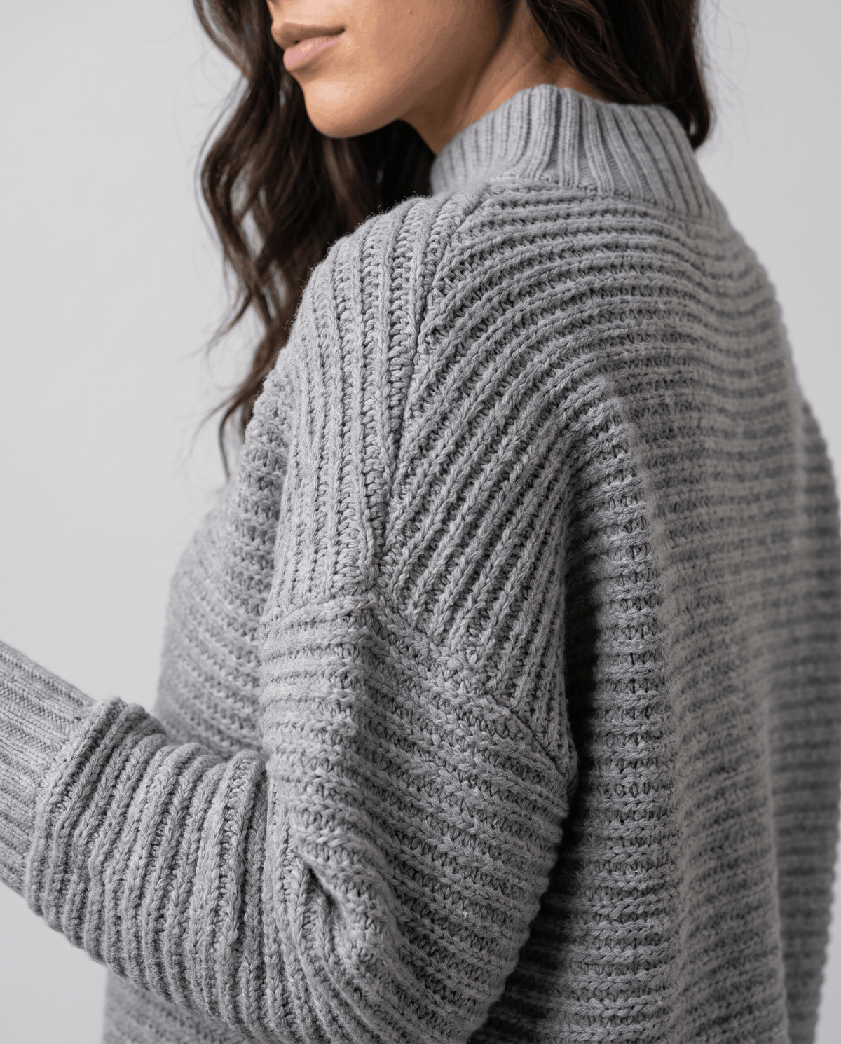Shoulder detail of gray chunky knit showing ribbed stand collar and texture