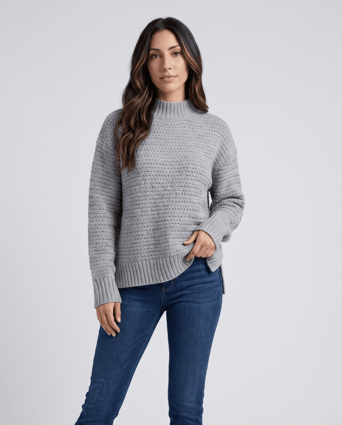 Front view of gray oversized mock neck sweater worn with dark jeans