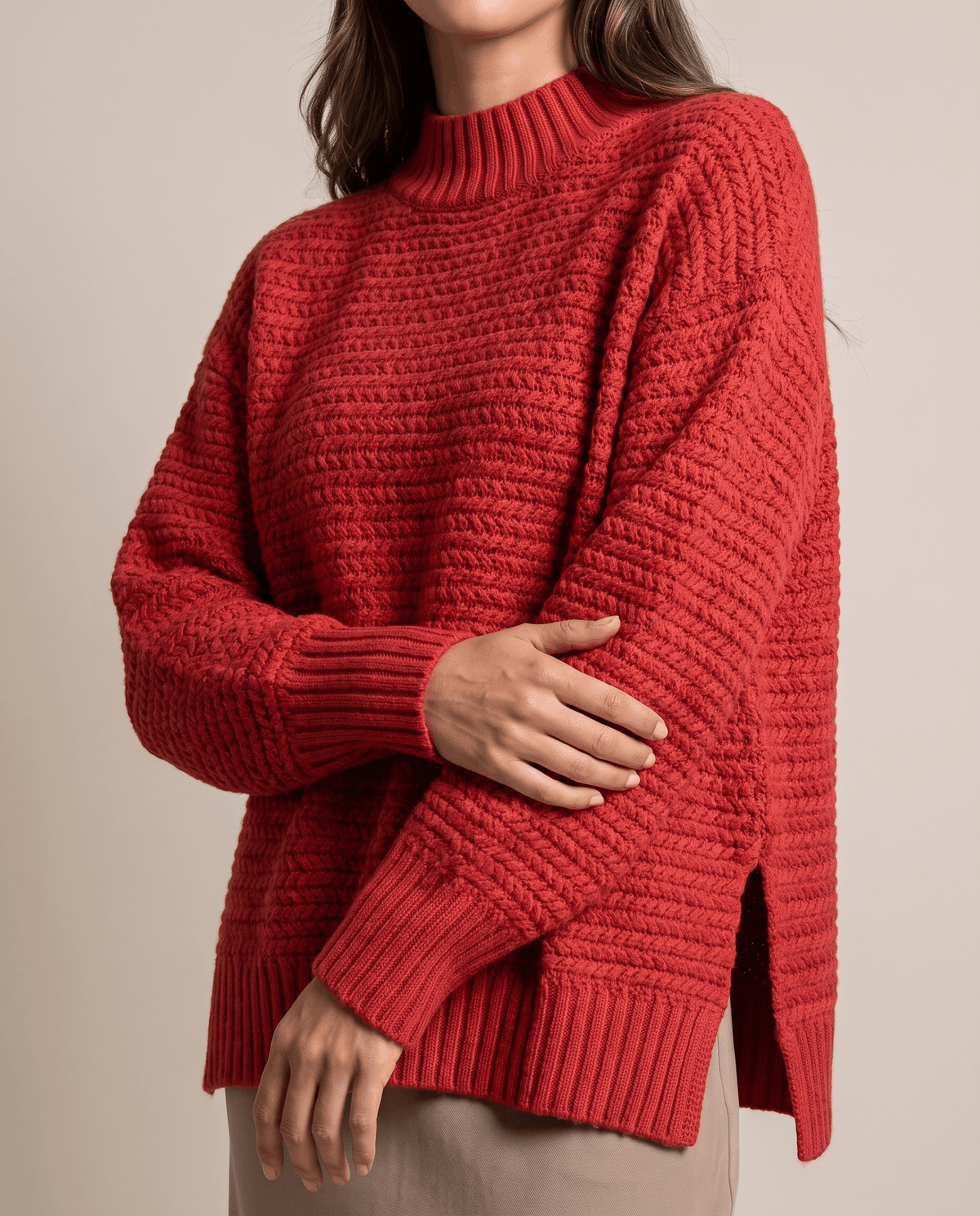 Cropped front view of red textured pullover showing the side slit hem