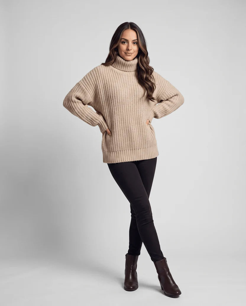 Full-length view of model in beige turtleneck sweater, black pants and brown boots