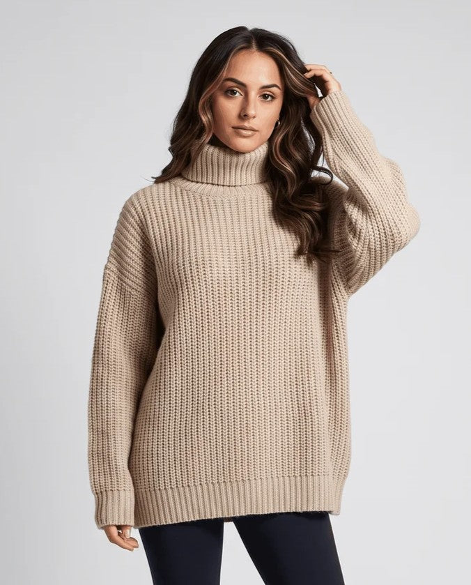 Model in dark beige ribbed turtleneck sweater with hand in hair, front view