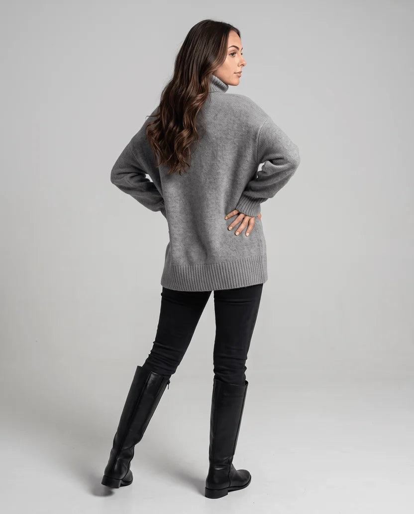 Full-length back view of model in gray sweater, black pants and tall boots