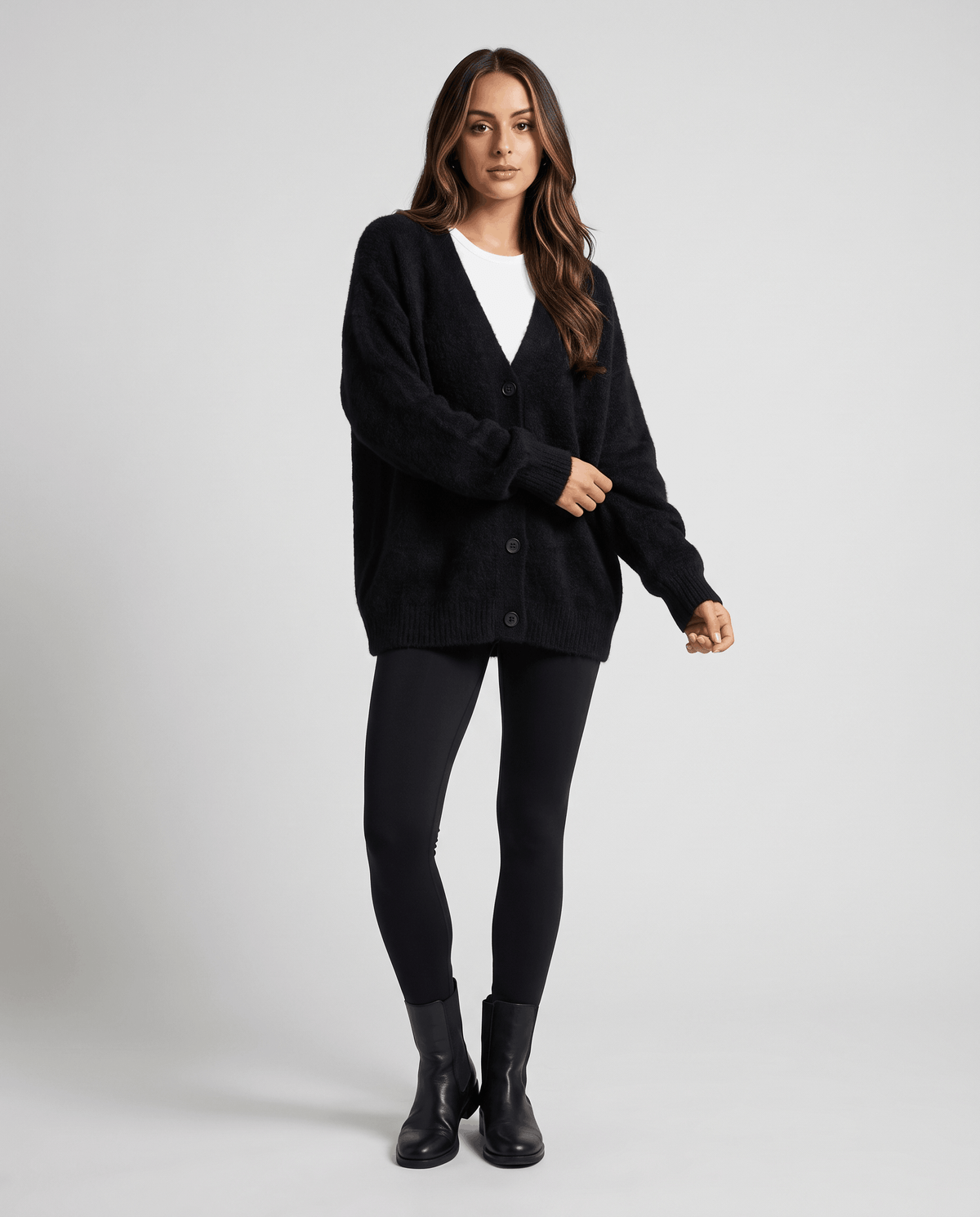 Black cardigan styled with black leggings, a white tee and black ankle boots