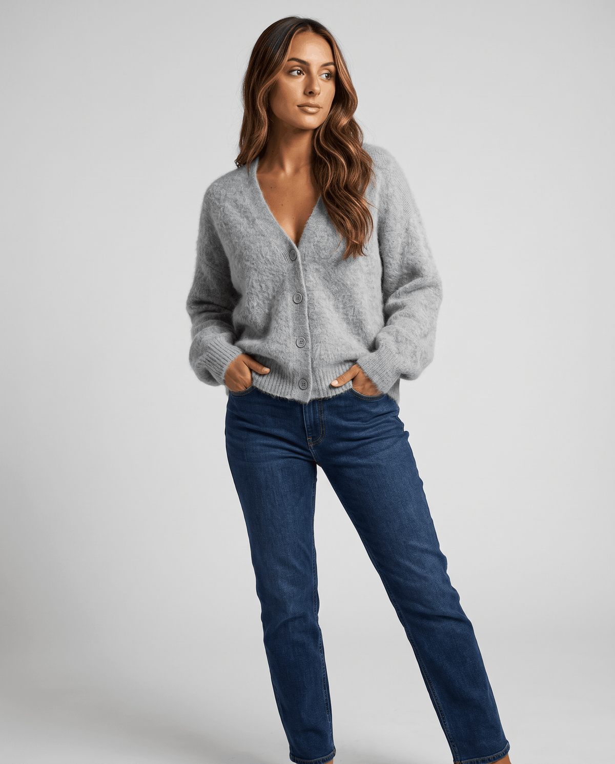 Full-length view of the gray cardigan styled with dark jeans and one hand in pocket