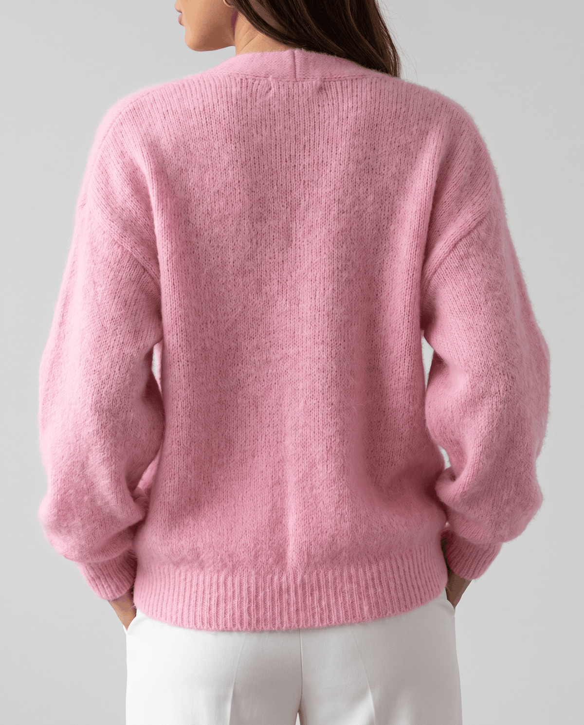 Back view of the pink cardigan with dropped shoulders and ribbed cuffs