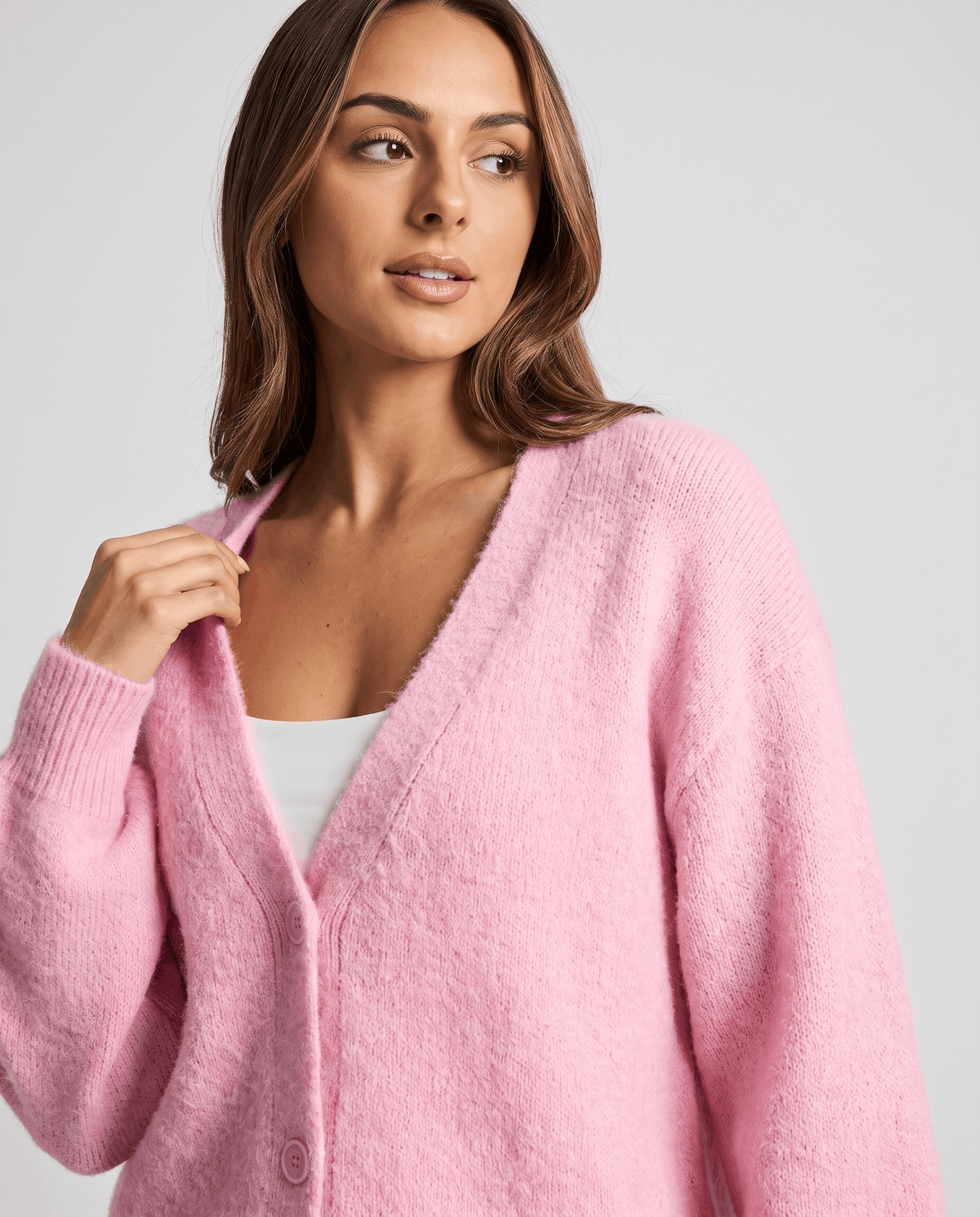 Close-up of the pink cardigan with a hand at the collar and front buttons
