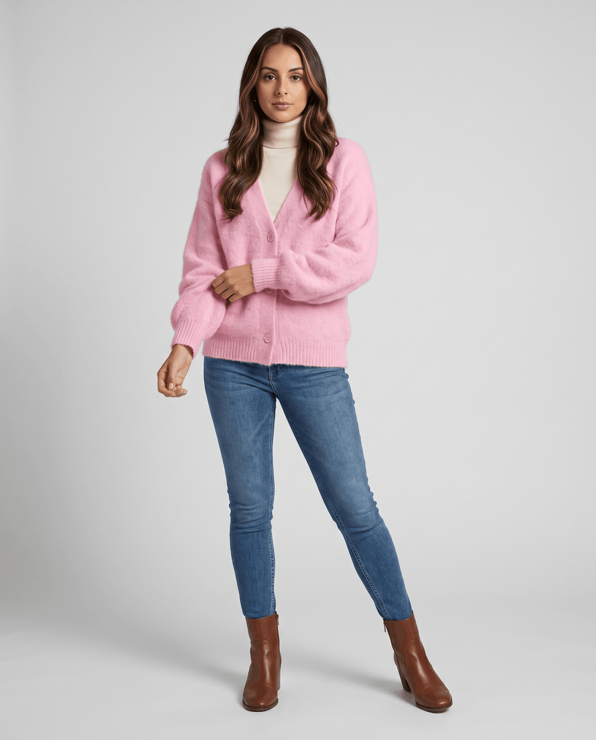 Pink cardigan over a white turtleneck with skinny jeans and brown ankle boots