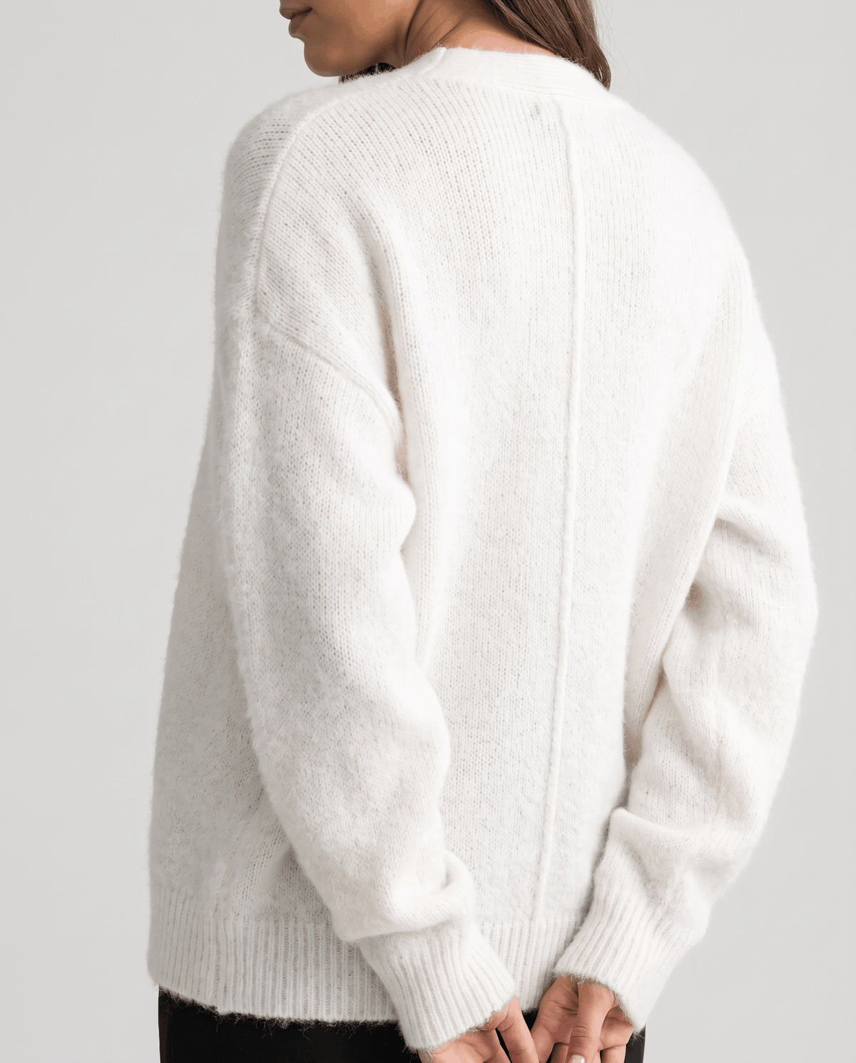 Back view of the white cardigan showing the ribbed hem and relaxed sleeves