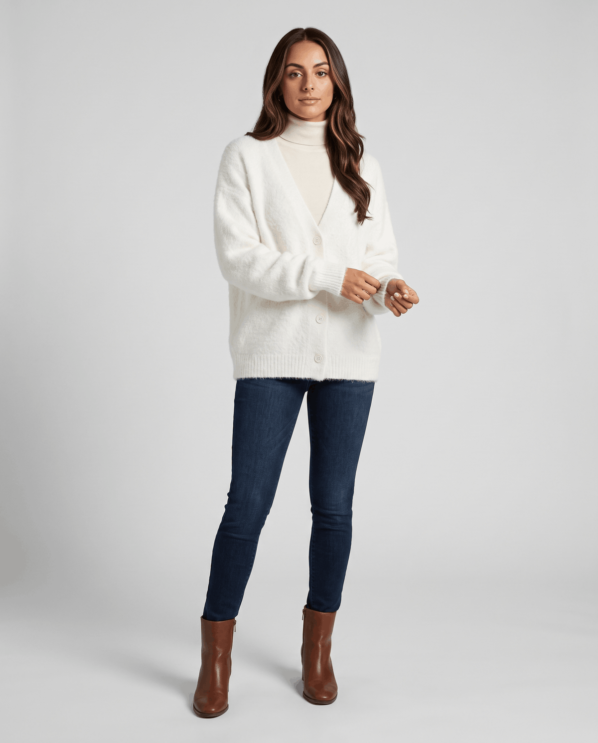 White cardigan styled with skinny jeans and brown heeled ankle boots