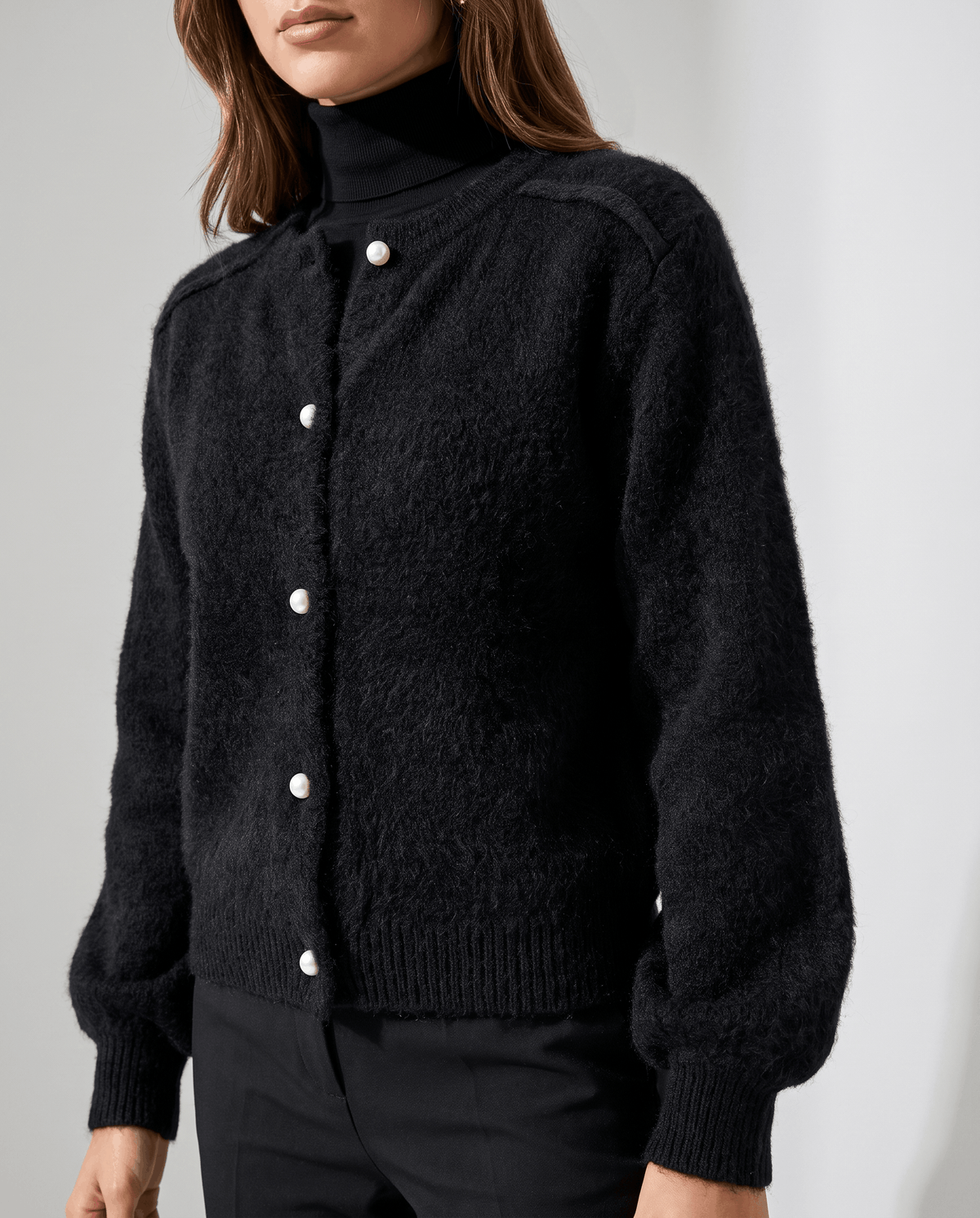 Front close-up of the black fuzzy cardigan buttoned over a black turtleneck
