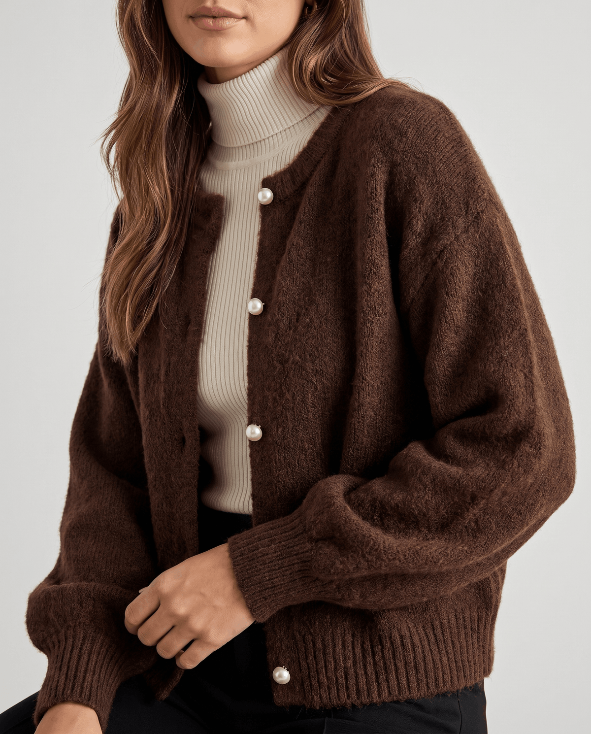 Brown fuzzy knit cardigan buttoned over a cream turtleneck, front close-up view