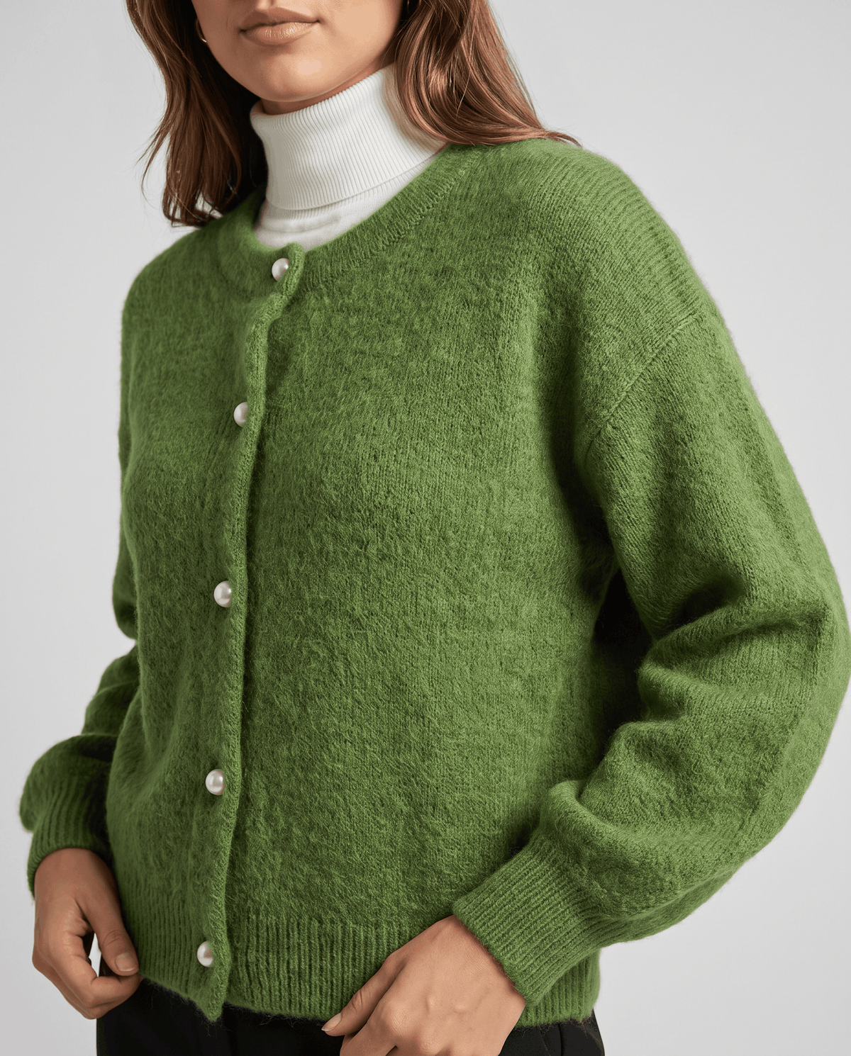 Front close-up of the green cardigan buttoned over a white turtleneck
