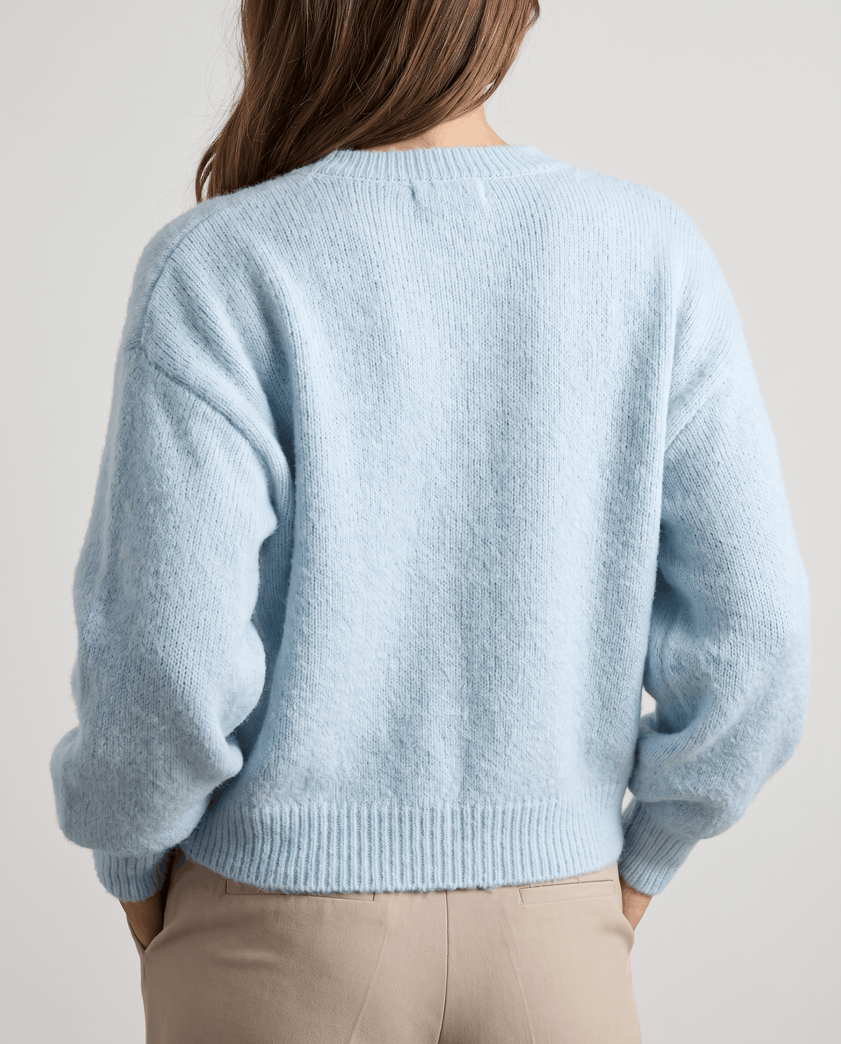 Back view of the light blue cardigan with a cropped ribbed hem and cuffs