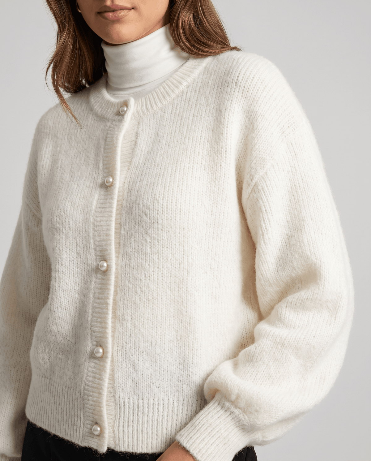 Front close-up of the white fuzzy knit cardigan buttoned over a white turtleneck