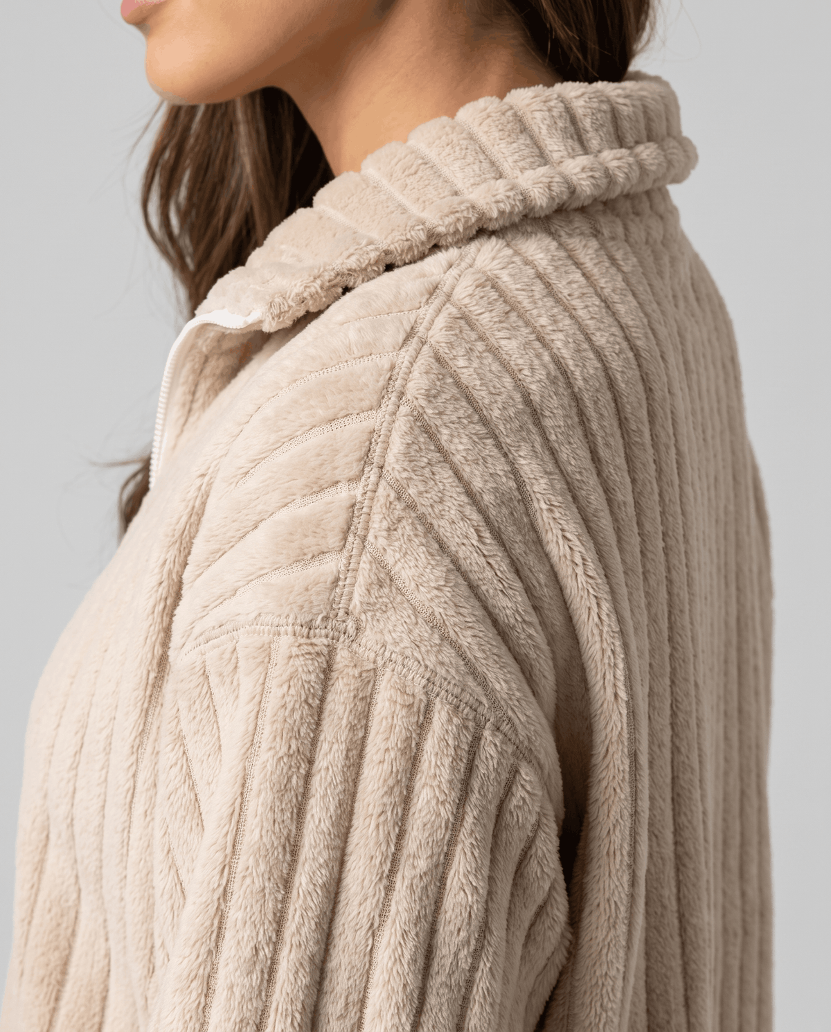 Side detail of wide plush ribs and folded stand collar in soft beige