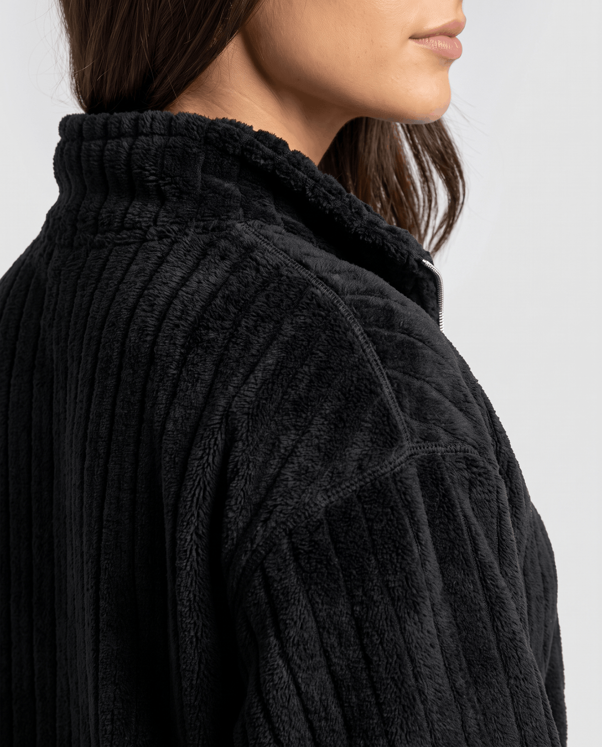Close-up of fuzzy black ribs and stand collar at the shoulder