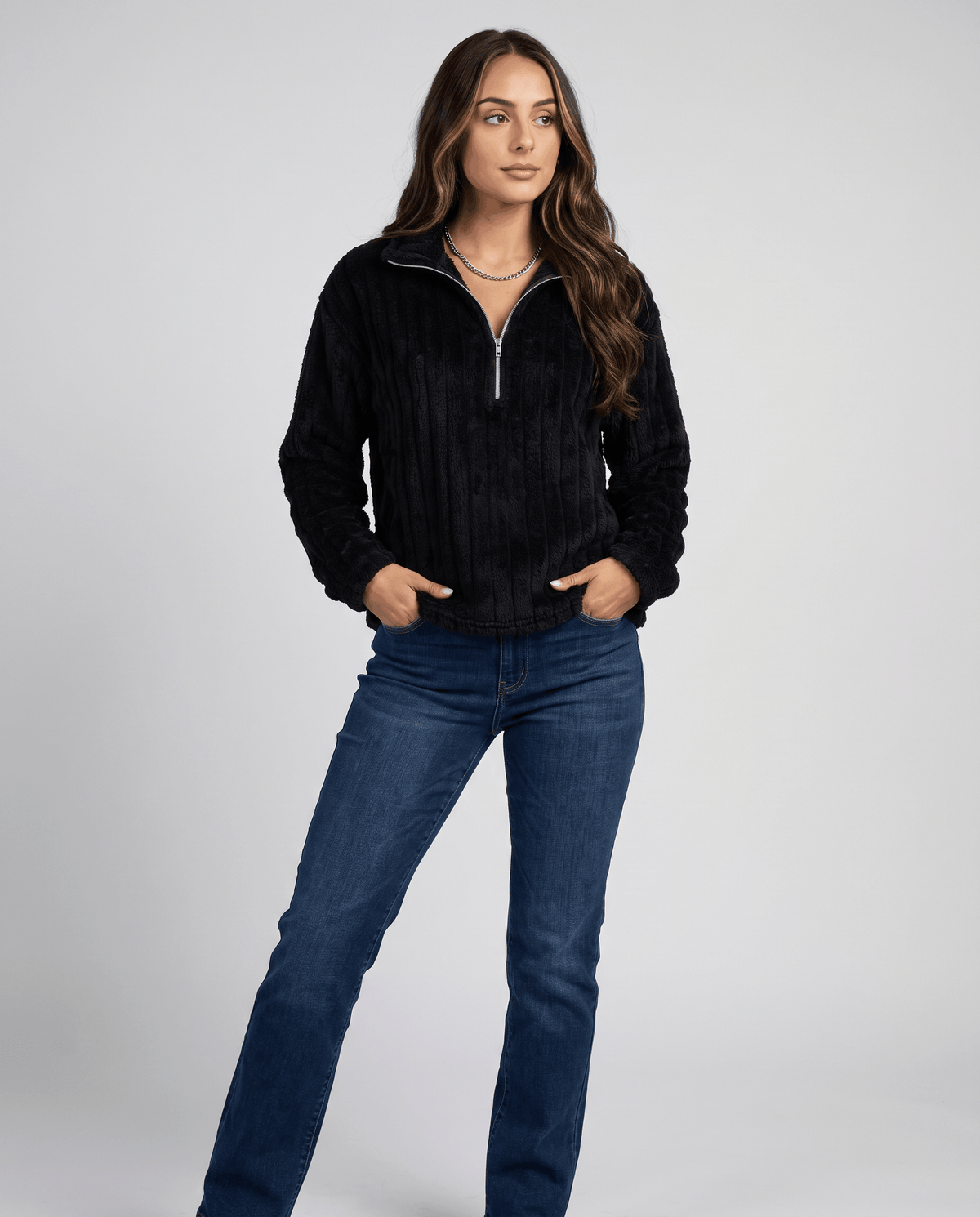 Full-length view of black ribbed pullover worn with dark jeans and boots