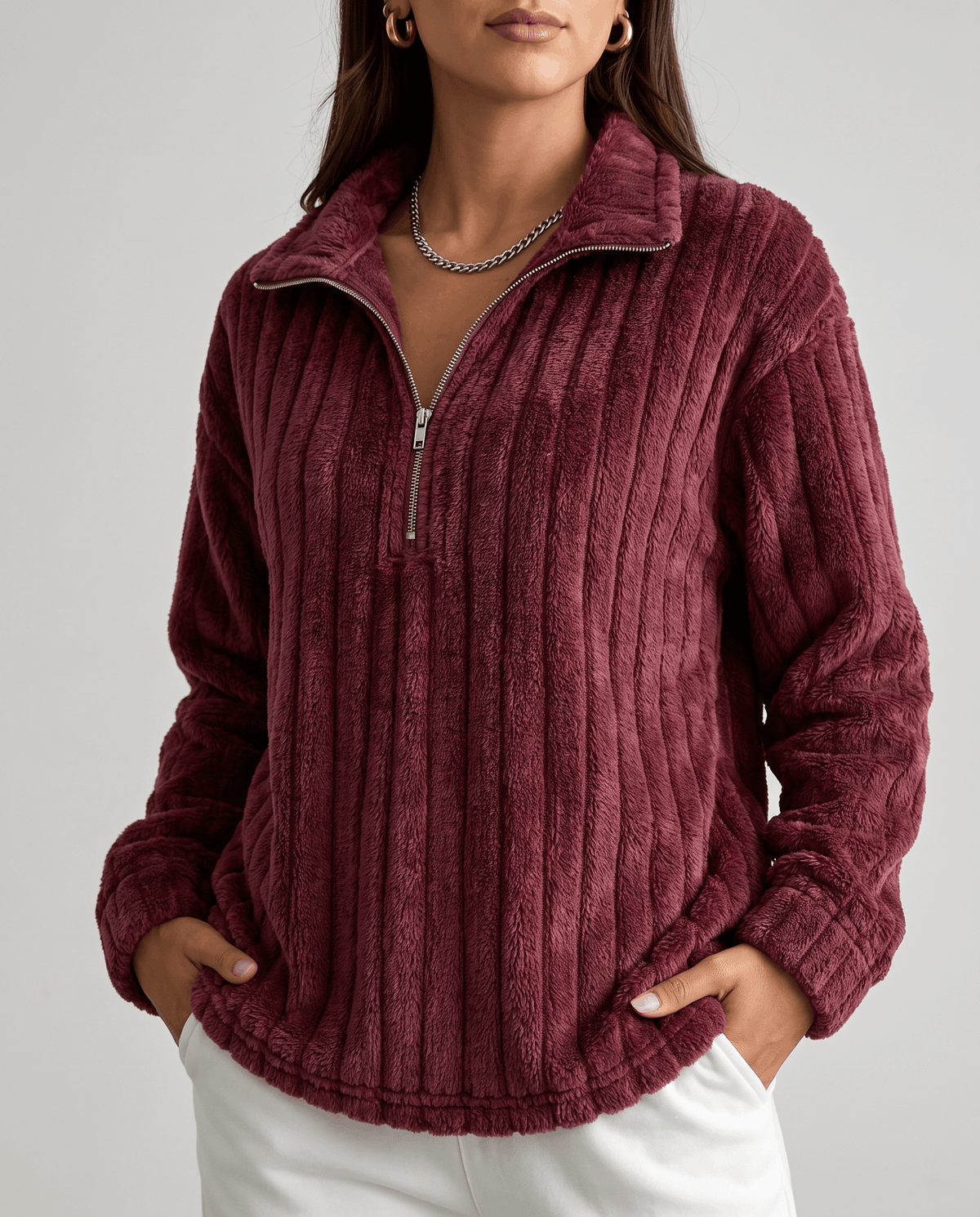 Cropped front view of burgundy ribbed pullover with zip open and white pants