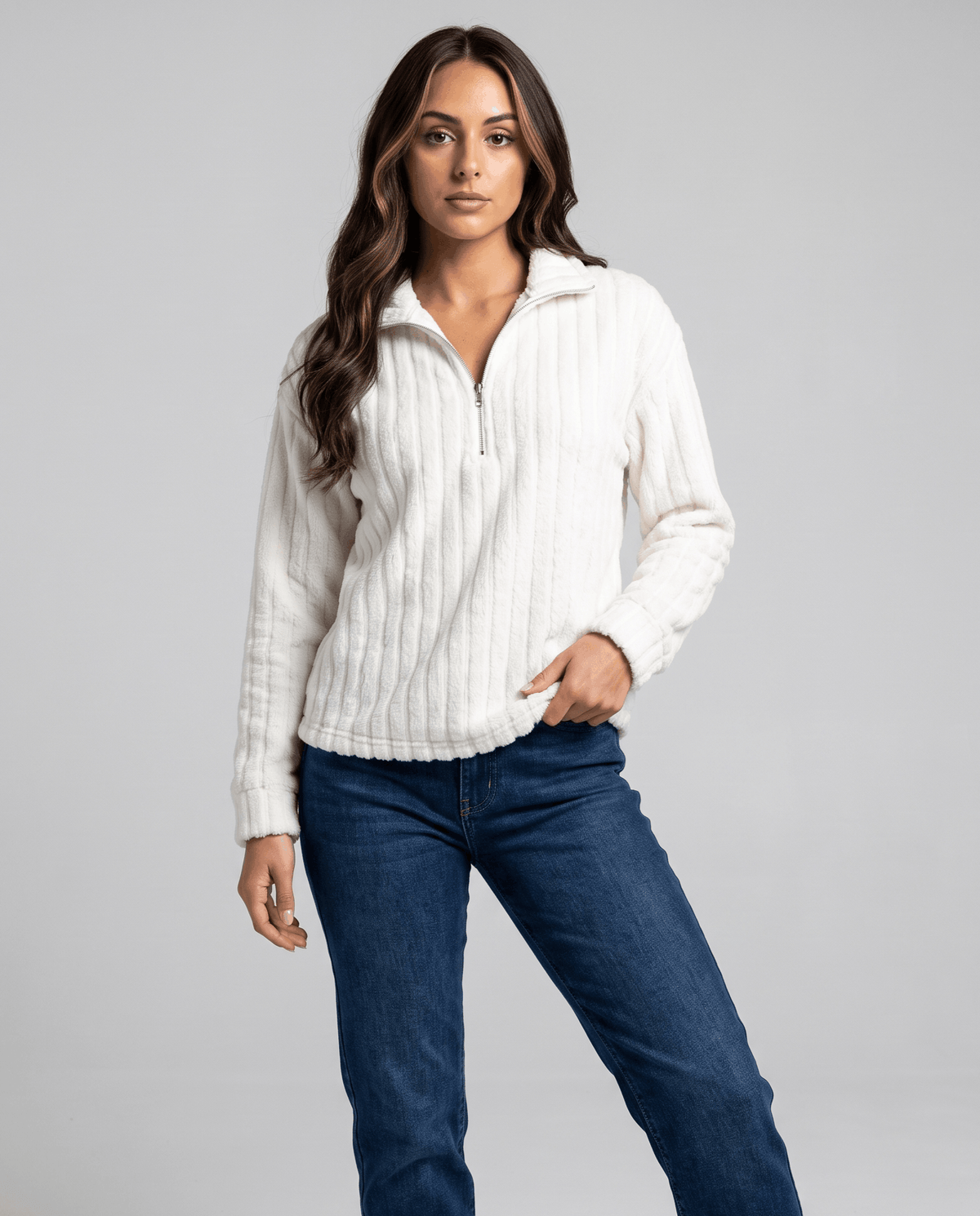 White ribbed zip-neck pullover worn with dark jeans, hand in jeans pocket