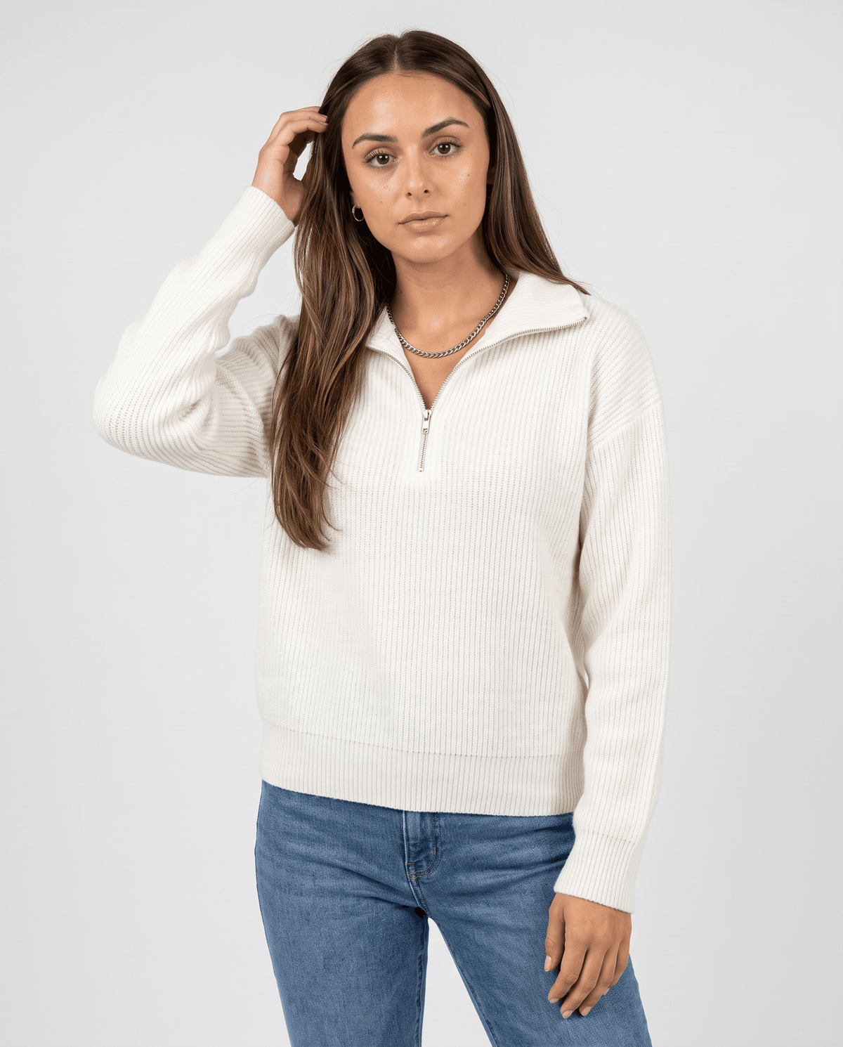Front view of white plush pullover with collar zipped halfway and light jeans