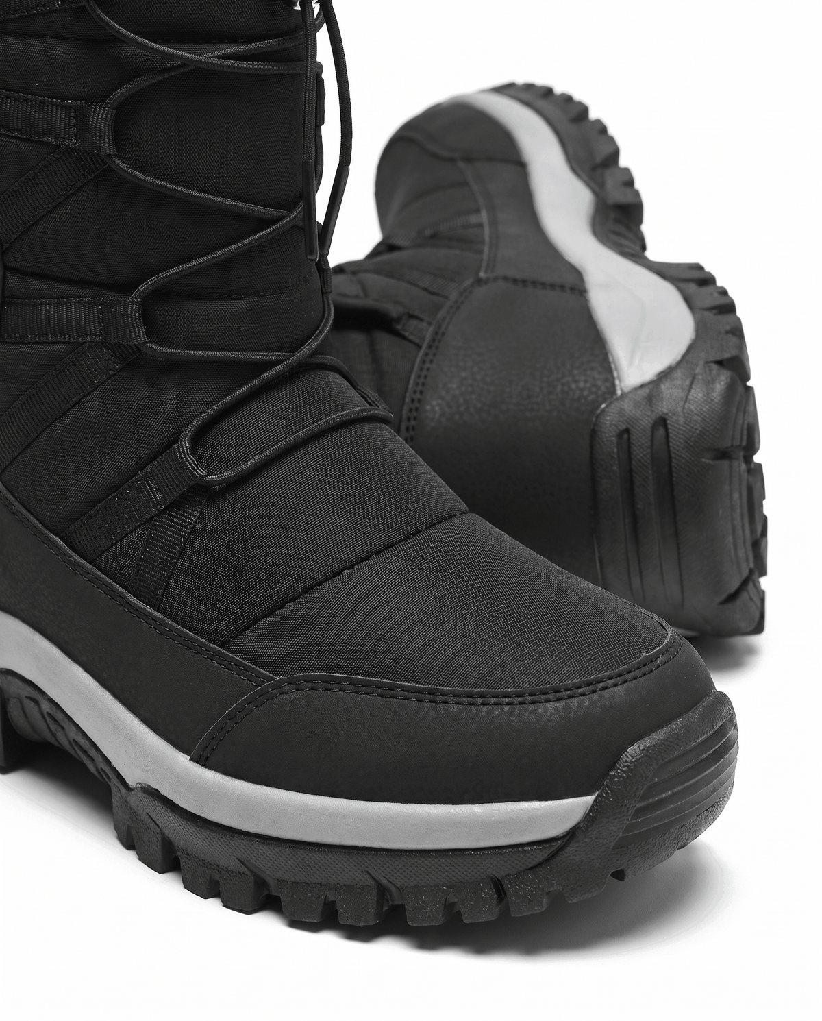 Close view of black quilted boot with drawstring cord and gray-striped lug sole