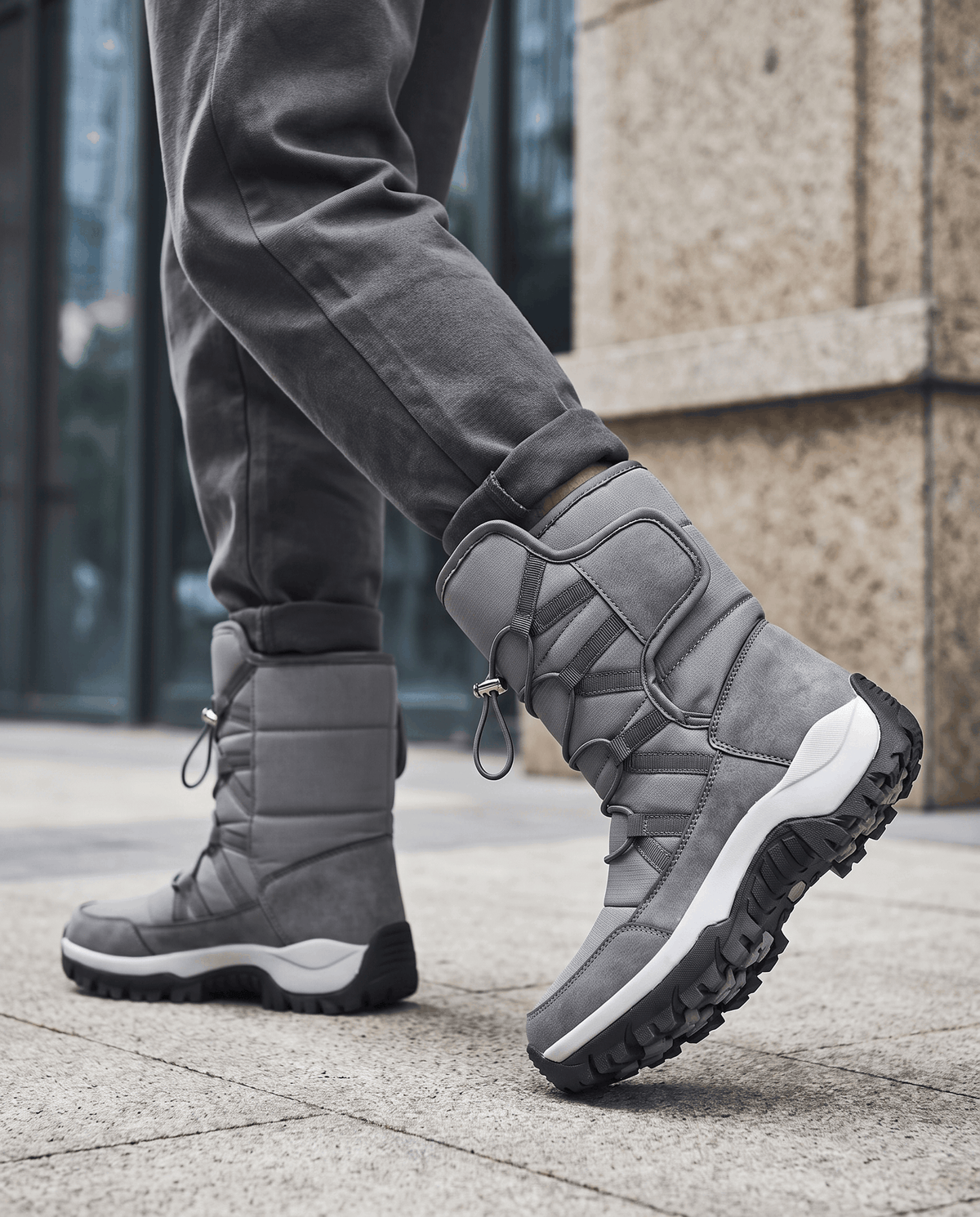 Gray quilted lug-sole boots worn with dark trousers on a paved sidewalk