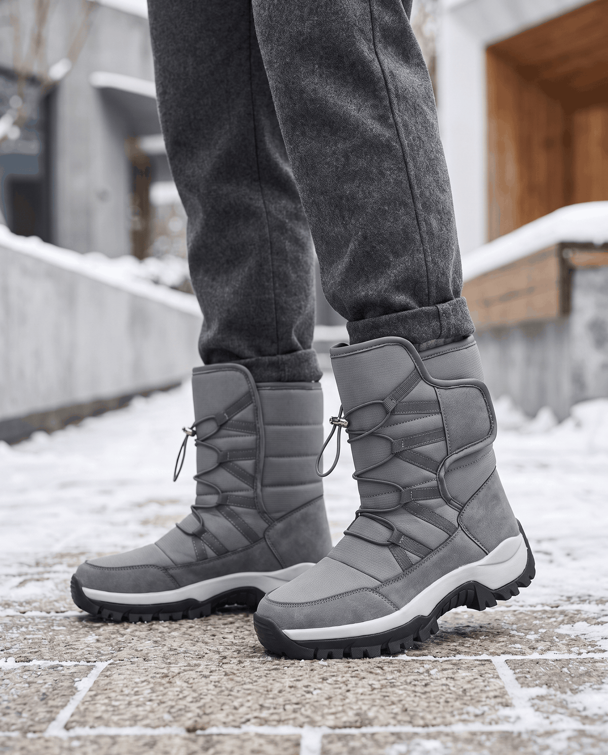 Man wearing gray quilted boots with dark jeans while walking along a city street