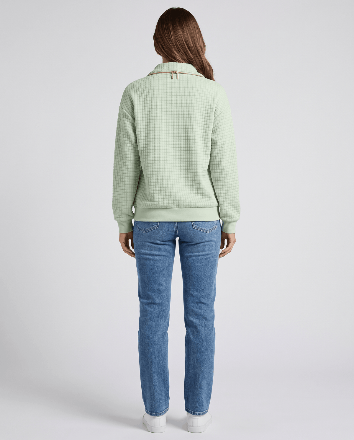 Full-length back view of mint green quilted pullover with light wash jeans