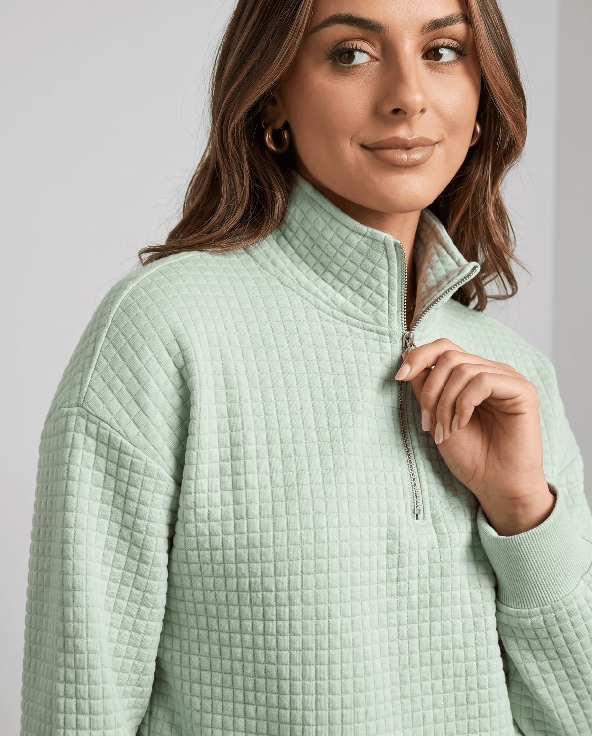 Close-up of model at the collar of a mint green zip-neck pullover