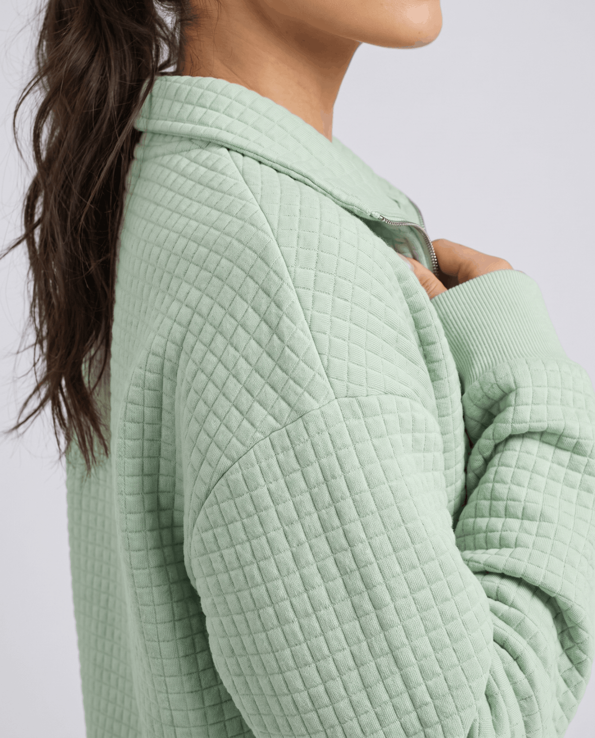 Shoulder detail showing square grid quilting on a mint green knit