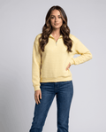 Woman wearing a yellow quilted quarter-zip pullover sweater with jeans, hand on hip