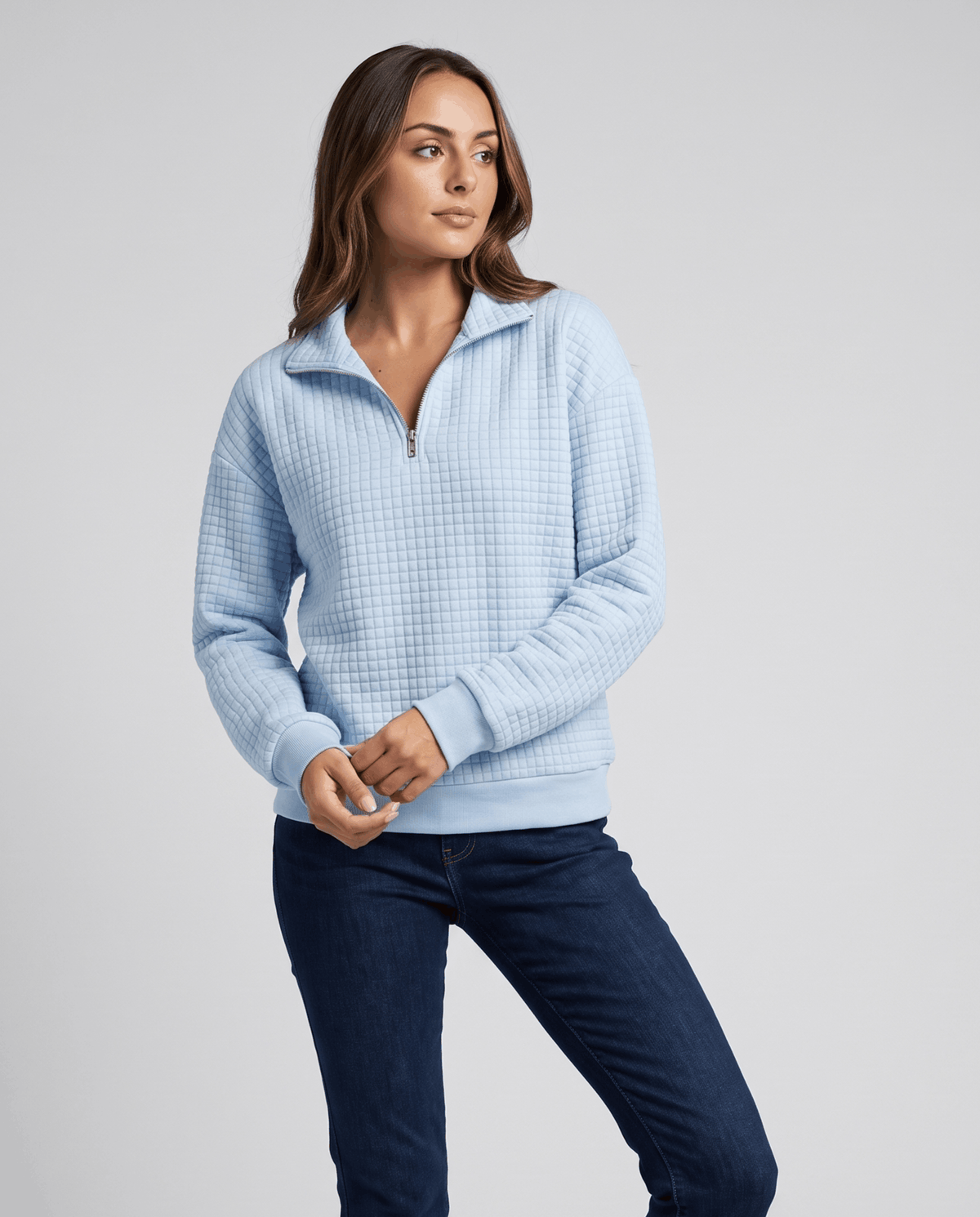Front view of sky blue quilted pullover styled with dark wash jeans