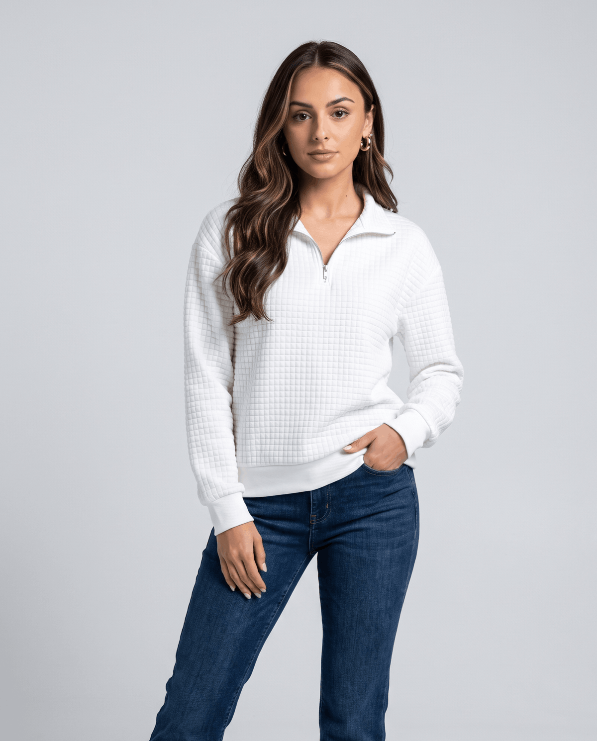Front view of white quilted pullover worn with dark jeans, hand in pocket