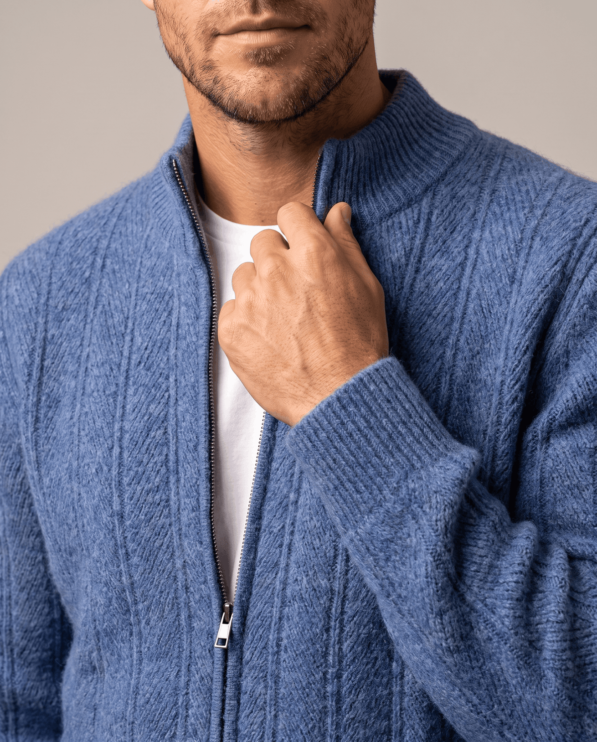 Close-up of a hand at the zip and stand collar of the blue cardigan