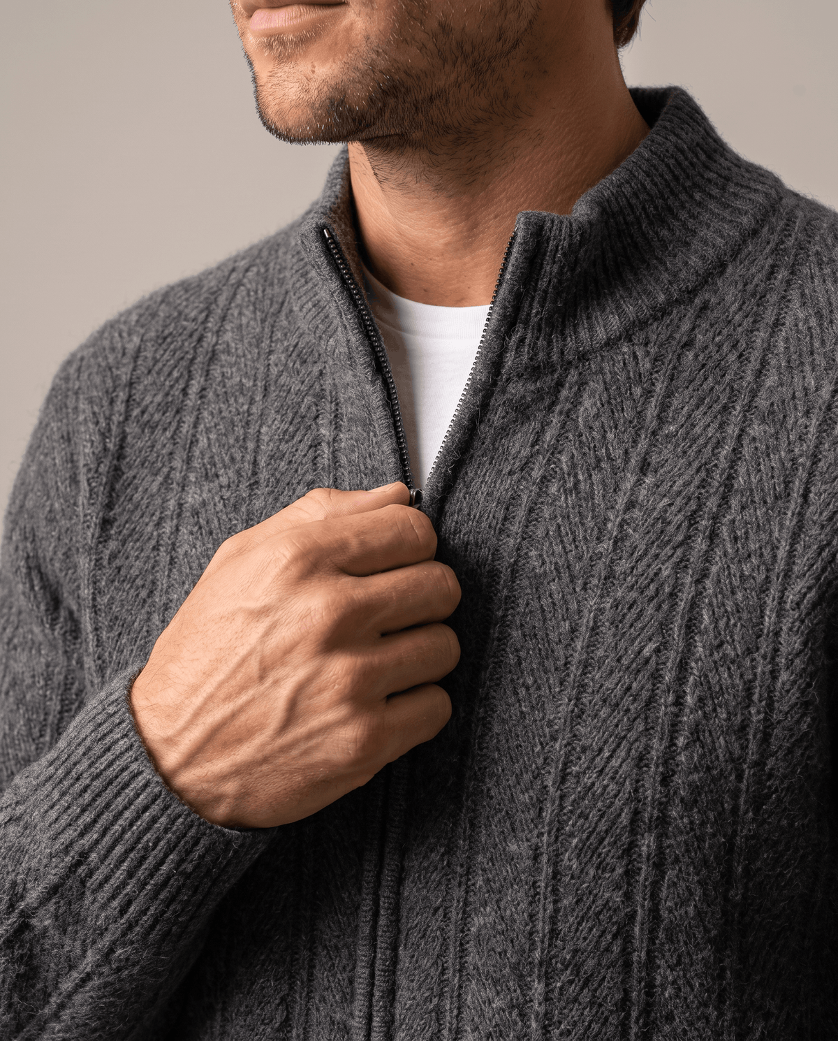 Close-up of a hand on the zip pull at the gray cardigan's stand collar