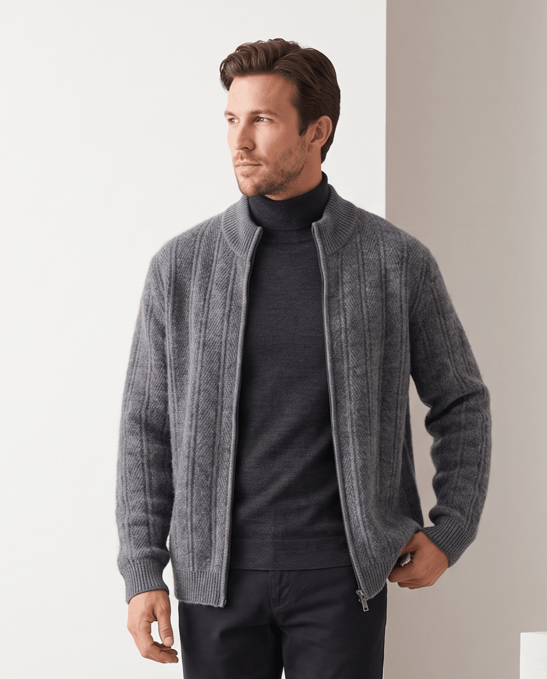 Gray cardigan zipped open over a black turtleneck with dark trousers