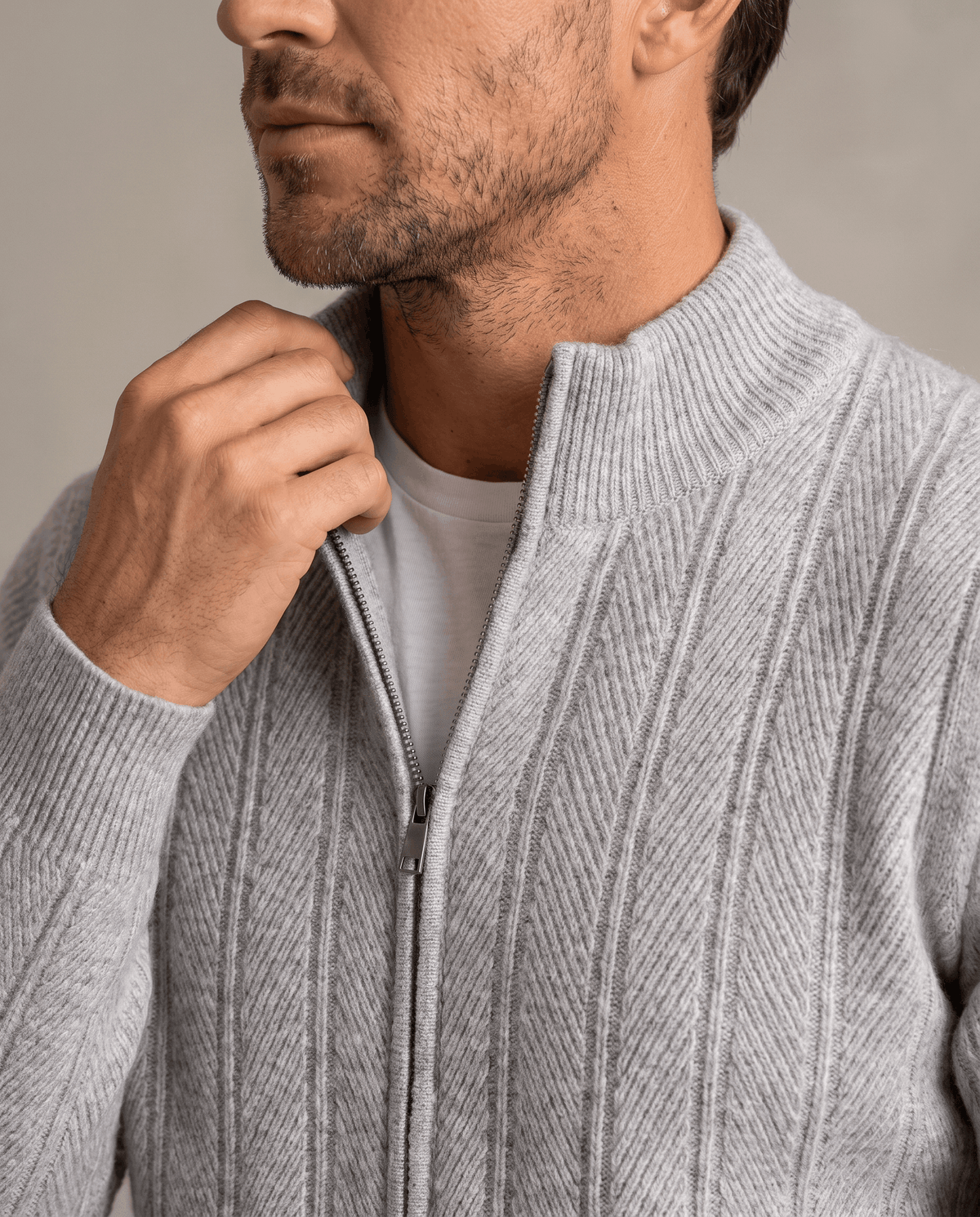 Close-up of a hand at the stand collar of the light gray ribbed knit cardigan