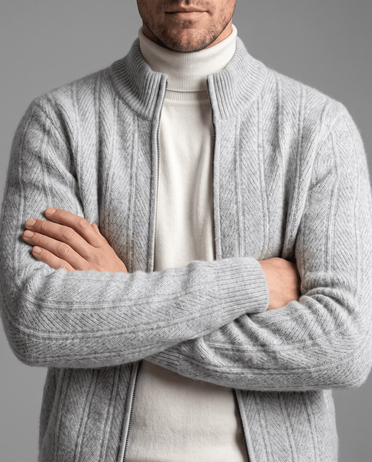 Light gray zip cardigan worn open over a cream turtleneck with arms crossed