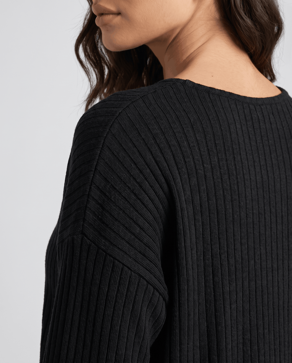 Close-up of the black ribbed knit texture at the neckline and shoulder