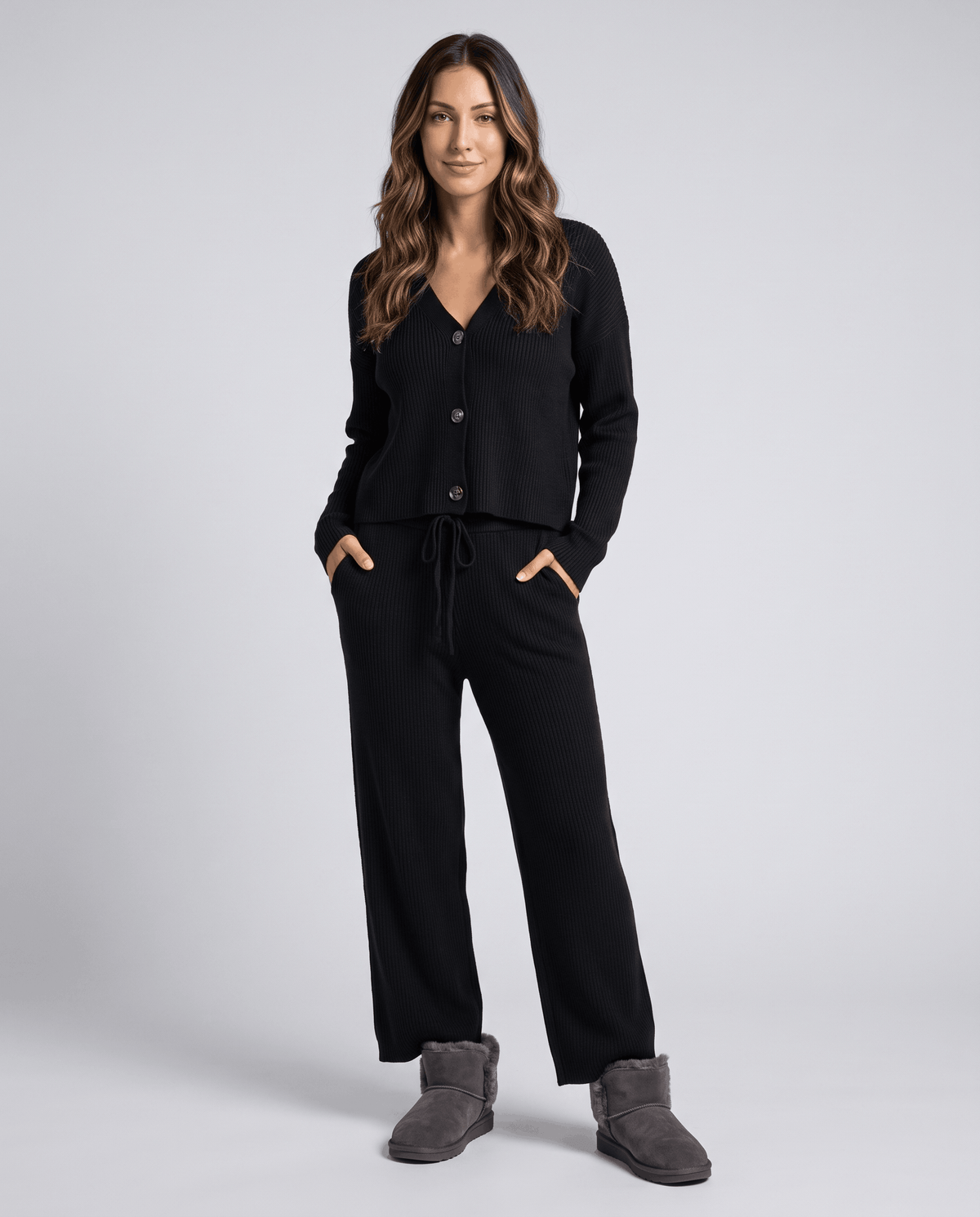 Black ribbed knit cardigan loungewear set with hands in the pants pockets, front view