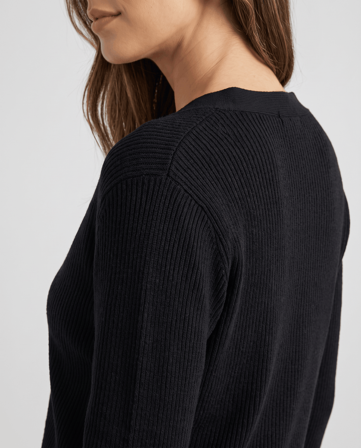 Close-up of the ribbed shoulder and sleeve on the black knit cardigan top