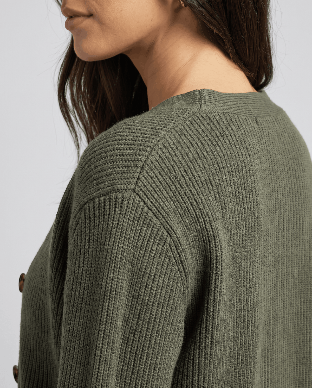 Close-up of the ribbed knit texture at the shoulder of the olive green cardigan